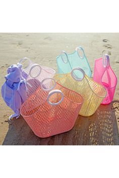 four plastic baskets sitting on top of a sandy beach