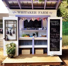 a white and purple food stand with chalk writing on it's side, outside