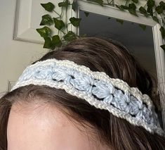 a woman wearing a crochet headband with leaves on the wall behind her