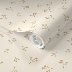 a white wallpaper with gold flowers and leaves on the side, next to a roll of paper