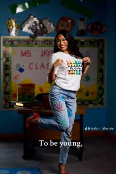 a young woman is posing in front of a classroom wall