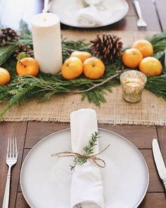 a place setting with oranges and pine cones