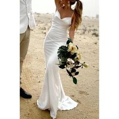 a woman in a white wedding dress holding a bouquet and standing next to a man