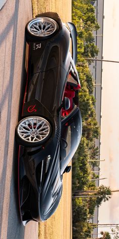 a black sports car parked on the side of a road next to a tall building