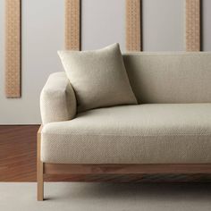 a couch with two pillows on it in front of some wooden frames and wood flooring