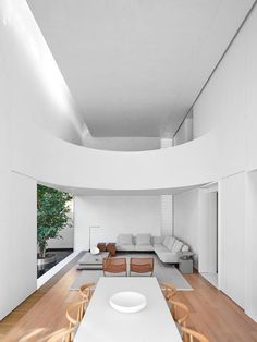 a living room with white walls and wooden flooring next to a dining table in front of a couch