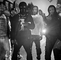 four young men standing together in the street