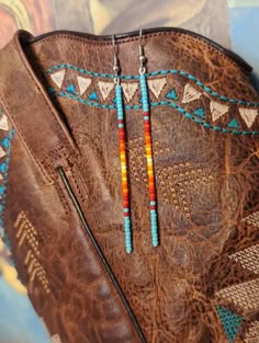 a pair of colorful beaded earrings sitting on top of a brown purse