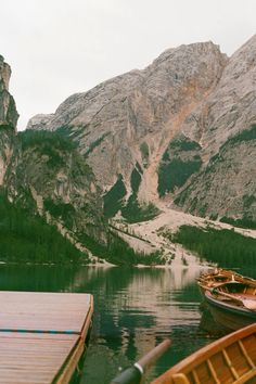 there are two boats that are docked in the water next to some rocks and mountains