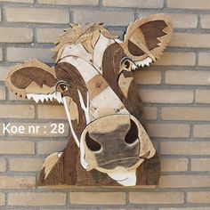 a wooden cow head mounted to the side of a brick wall with text above it that reads koe n 28