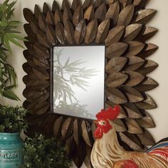 a mirror mounted to the side of a wall with a rooster statue next to it