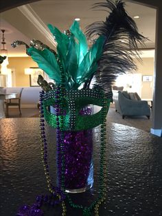 a mardi gras decoration with beads and feathers in a vase on a table