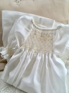 Hand Smocked Baby Day Gown to suit Newborn to 6 months approx. (depends on child) Made in a fine Ivory/Off White 100% Cotton Voile fabric with buttons down the back to close. Hand smocked and embroidered at the front between the raglan sleeves in ivory and ecru, with a bound neckline hand embroidered with featherstitching and smocked sleeves with fine cotton lace trim. Raglan sleeves allow for a longer wear time and are smocked and edged with fine cotton lace trim. Daygown measures 55cm (21 1/2" Classic White Smocked Dress, Cream Dress With Smocked Bodice For Wedding, Elegant White Smocked Back Dress, White Smocked Dress With Lace Trim For Daywear, Elegant White Smocked Dress For Daywear, Elegant White Smocked Dress, White Fitted Smocked Dress For Baptism, Elegant Fitted Baptism Dress With Smocked Bodice, Elegant Smock Dresses For Baptism