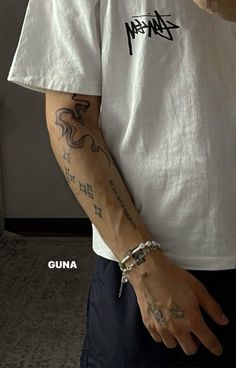 a man with tattoos on his arm wearing a white t - shirt