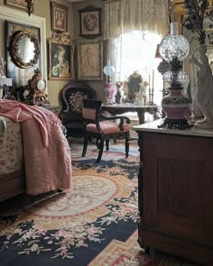 a bedroom with antique furniture and paintings on the walls, along with an ornate rug