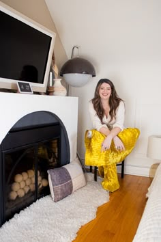 a woman sitting on a chair in front of a fireplace