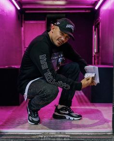 a man kneeling down in front of a purple light holding a box with something on it