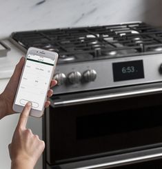 a woman is using her phone to check out the appliance in front of an oven