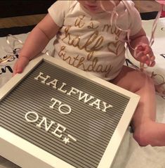 a baby sitting in front of a cake with the words halfway to one on it