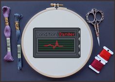 a cross stitch pattern with scissors, thread and needle on the table next to it