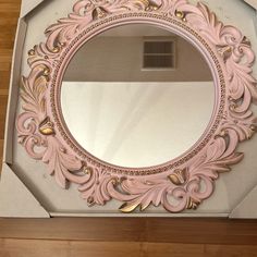 a pink mirror sitting on top of a wooden floor