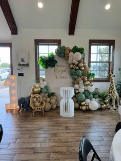 a room decorated with balloons and greenery for a baby's first birthday party