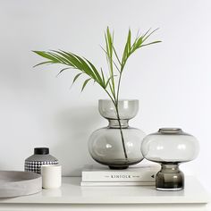 a white table topped with two vases and a plant on top of a book