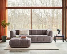 a living room with large windows and a gray couch in front of a white rug