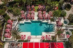 an aerial view of a pool with red and white umbrellas