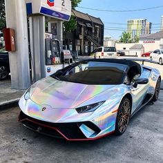 a silver sports car parked in front of a gas station with holographic paint on it