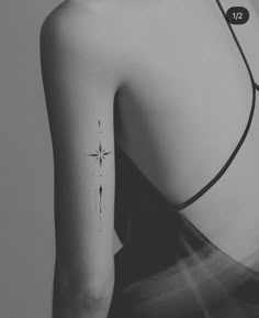 the back of a woman's shoulder with a small star tattoo on her left arm