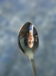 the reflection of a woman in a mirror on a spoon is seen through it's side view mirror