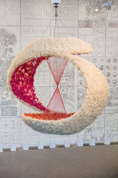 a room with a large wall hanging made out of fabric and yarn, in the shape of a moon