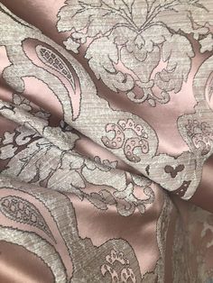 a close up view of a pink and brown fabric with flowers on the side, as well as an intricate design