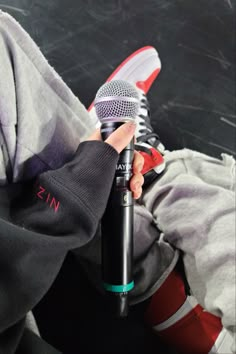 a person holding a microphone in their left hand and wearing red shoes on the other