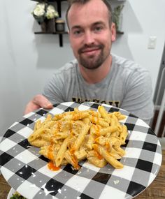 a man sitting at a table in front of a plate of food that includes macaroni and cheese