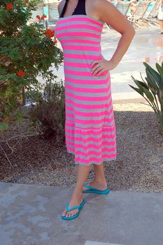 a woman in a pink and black striped dress posing for the camera with her hands on her hips