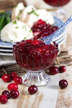 cranberry sauce in a glass bowl with ice cream and cherries around it