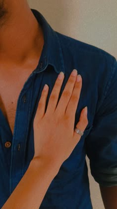 a close up of a person holding their hand on his chest and wearing a ring