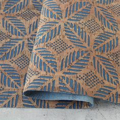 a blue and brown wallpaper with leaves on it's side, next to a pair of jeans