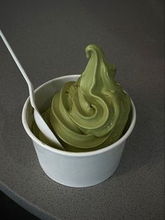 a white bowl filled with green cream on top of a counter