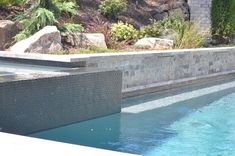 an outdoor swimming pool surrounded by rocks and plants