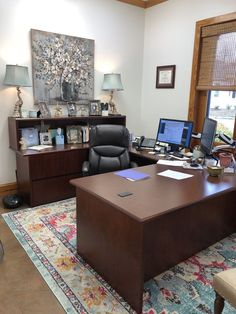 a home office with two computers on the desk and a large rug in front of it