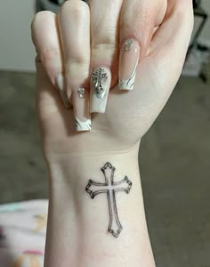 a woman's wrist with a cross tattoo on it