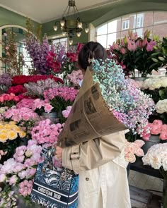 a woman looking at flowers in a flower shop with a newspaper over her shoulder,