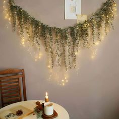 a string of lights hanging from the side of a wall next to a candle on a table