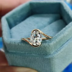 a close up of a person's hand holding an engagement ring in a box