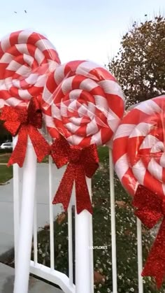 some lollipops are tied to white poles with red bows and glitter ribbons