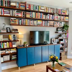 a living room with bookshelves full of books and a flat screen tv on the wall