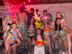 a group of people standing around each other in bathing suits with neon lights on them